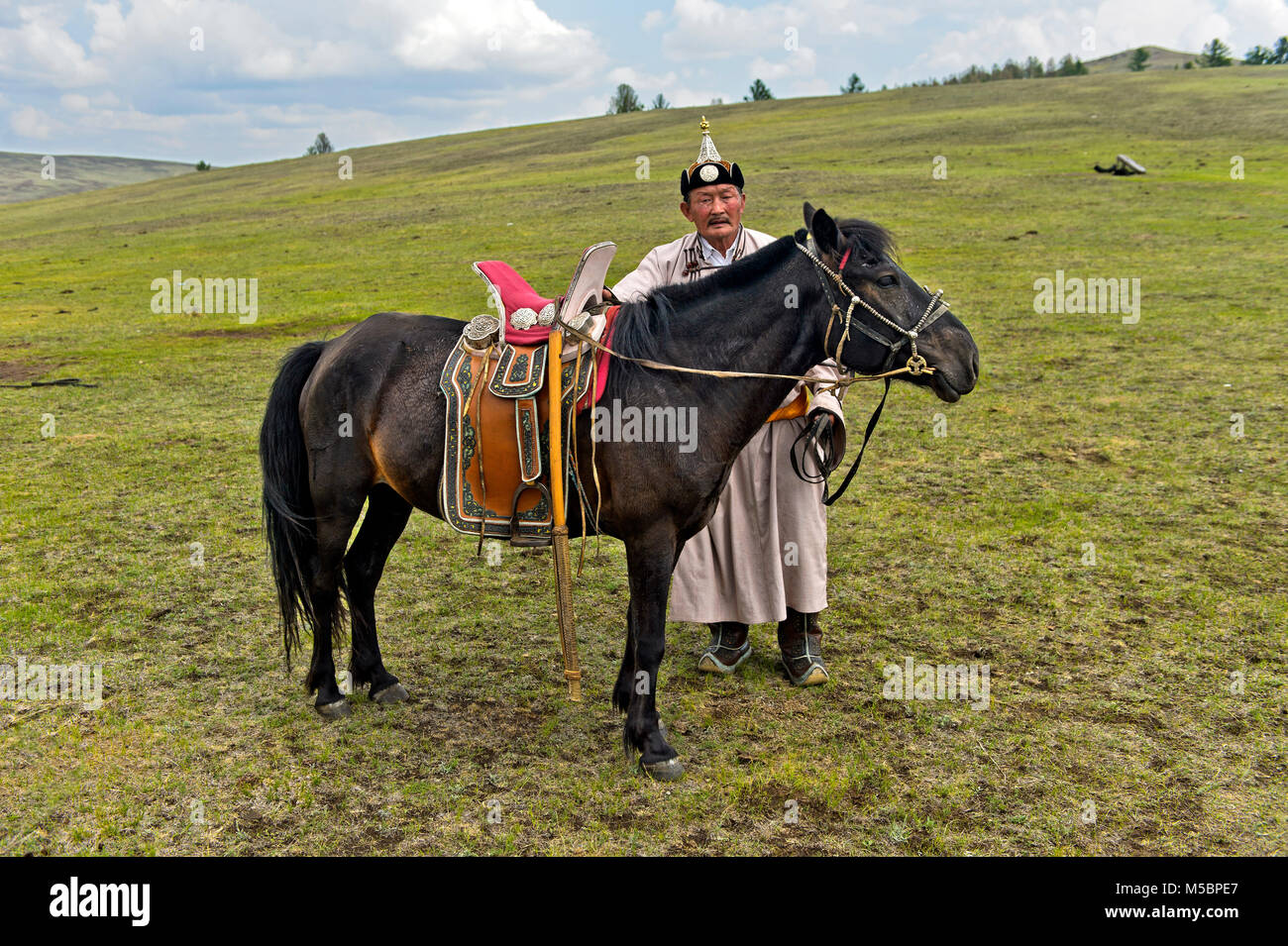 Nomad âgés de sexe masculin en costume traditionnel avec son cheval bridée dans la steppe, près de Erdenet, Mongolie Banque D'Images