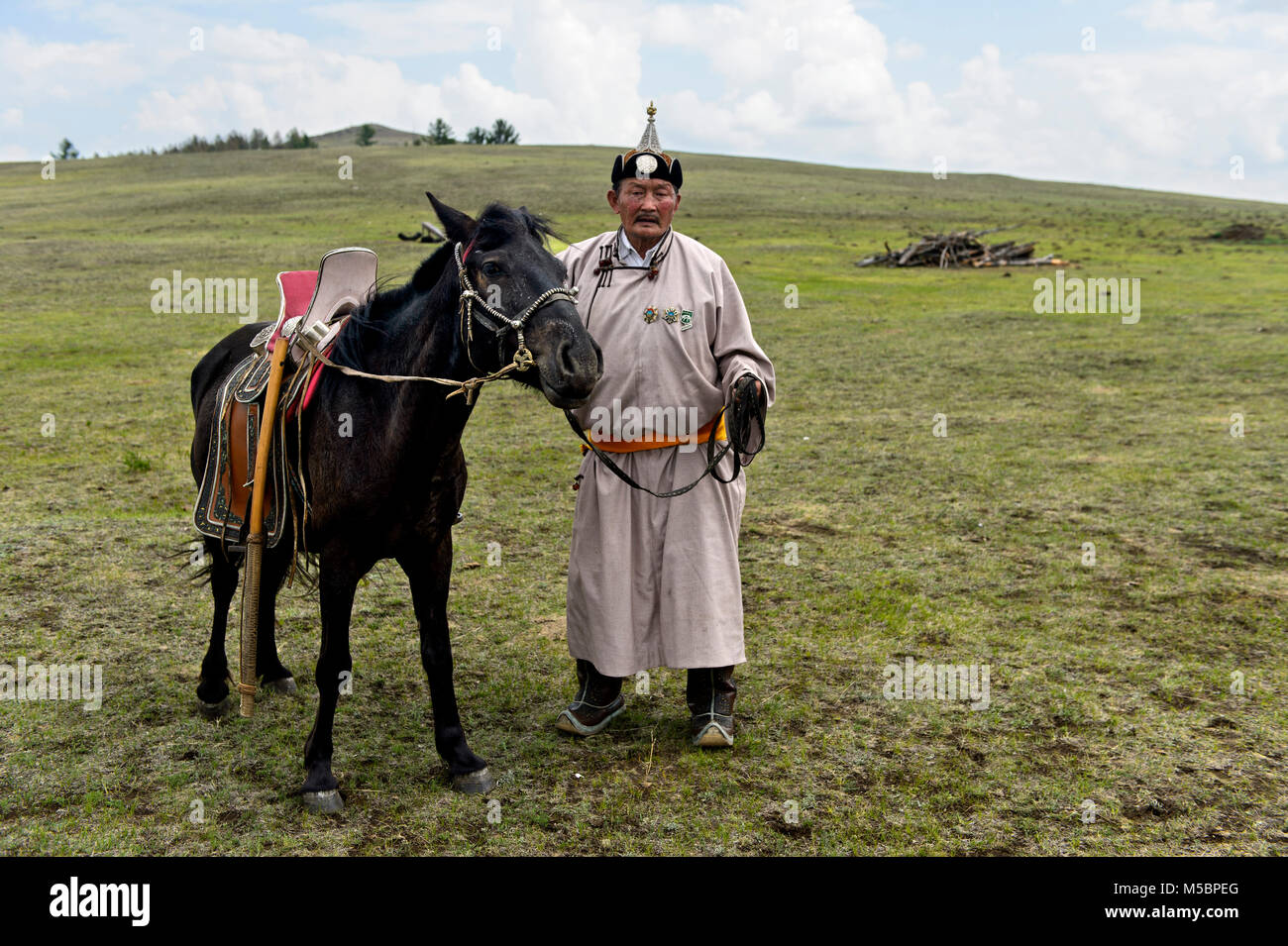 Nomad âgés de sexe masculin en costume traditionnel avec son cheval bridée dans la steppe, près de Erdenet, Mongolie Banque D'Images