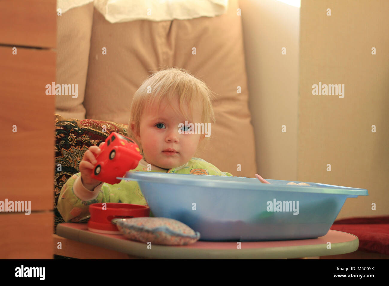 Portrait d'une petite fille blonde aux yeux bleus avec ses jouets à la maison Banque D'Images