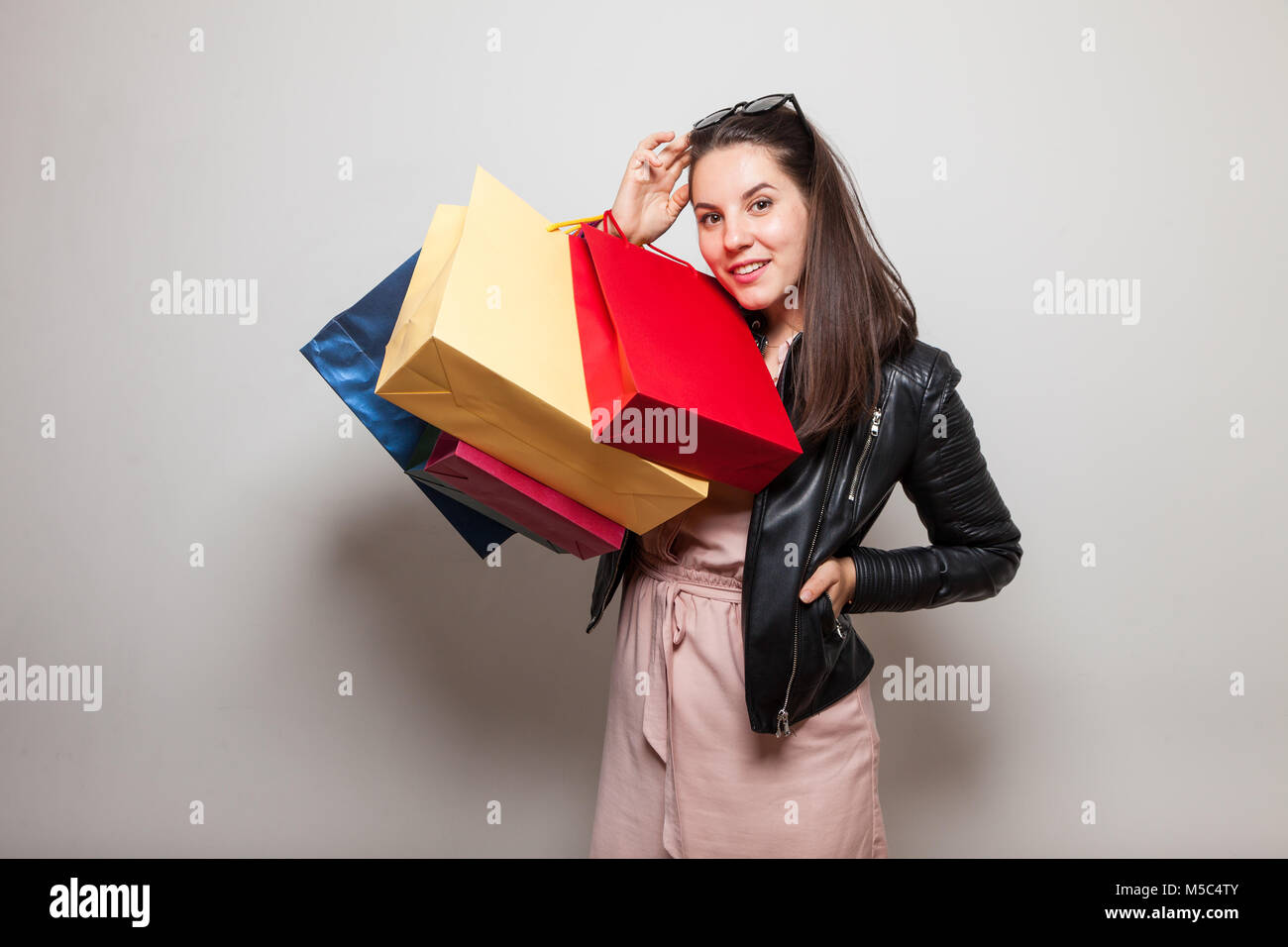 Jolie femme en robe rose et veste en cuir sacs détient Banque D'Images