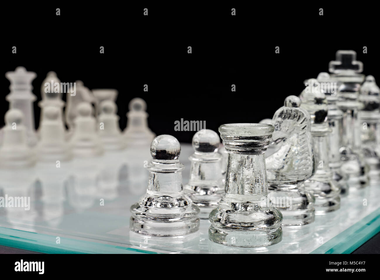 Échecs de l'échiquier en verre avec des pions sur un fond noir Banque D'Images