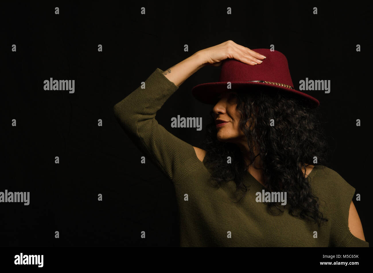 La lumière artificielle, travailler en studio, une femme heureuse avec un chapeau dans sa main, Banque D'Images