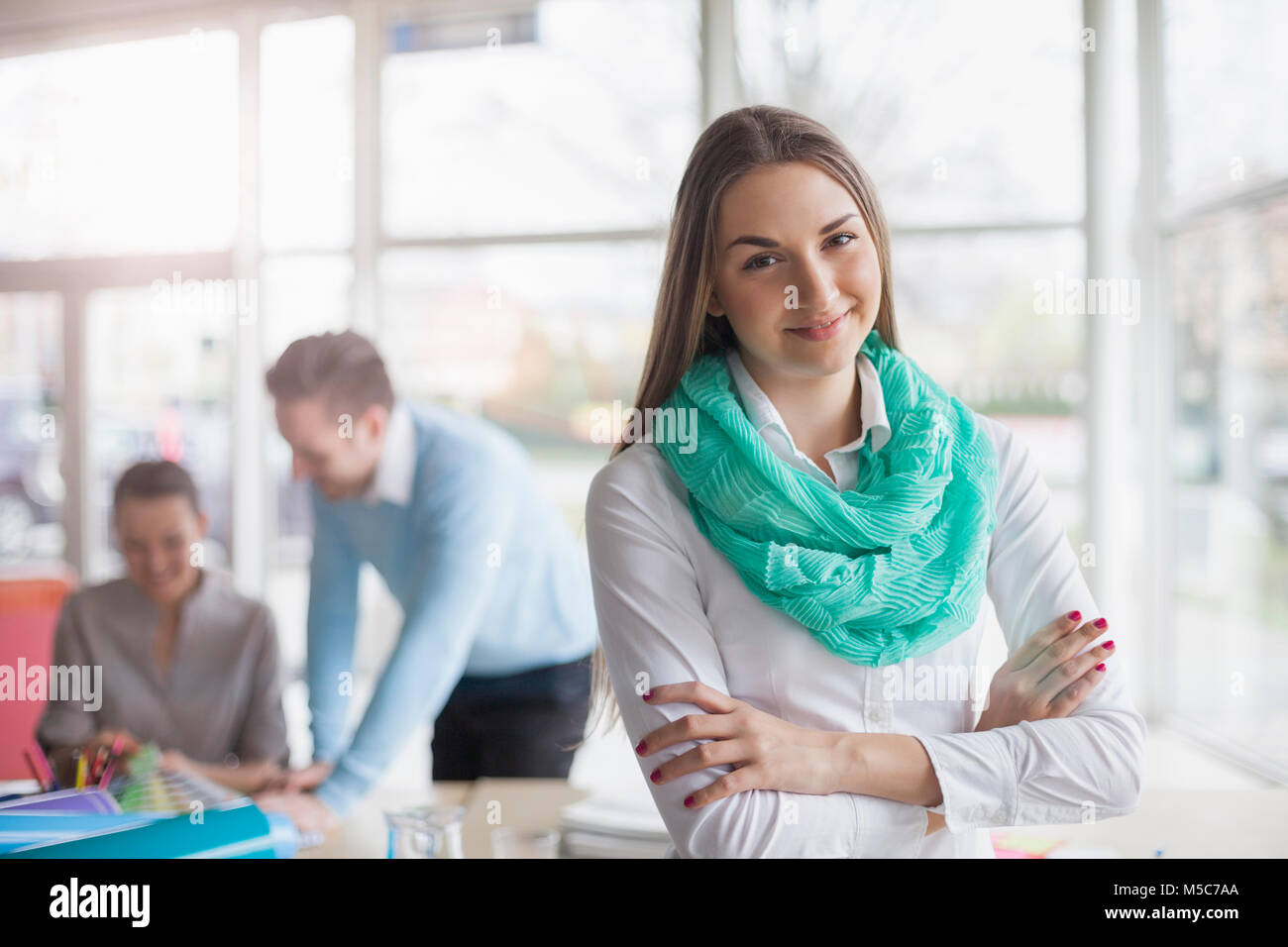 Portrait of young businesswoman with colleagues discussing in background Banque D'Images