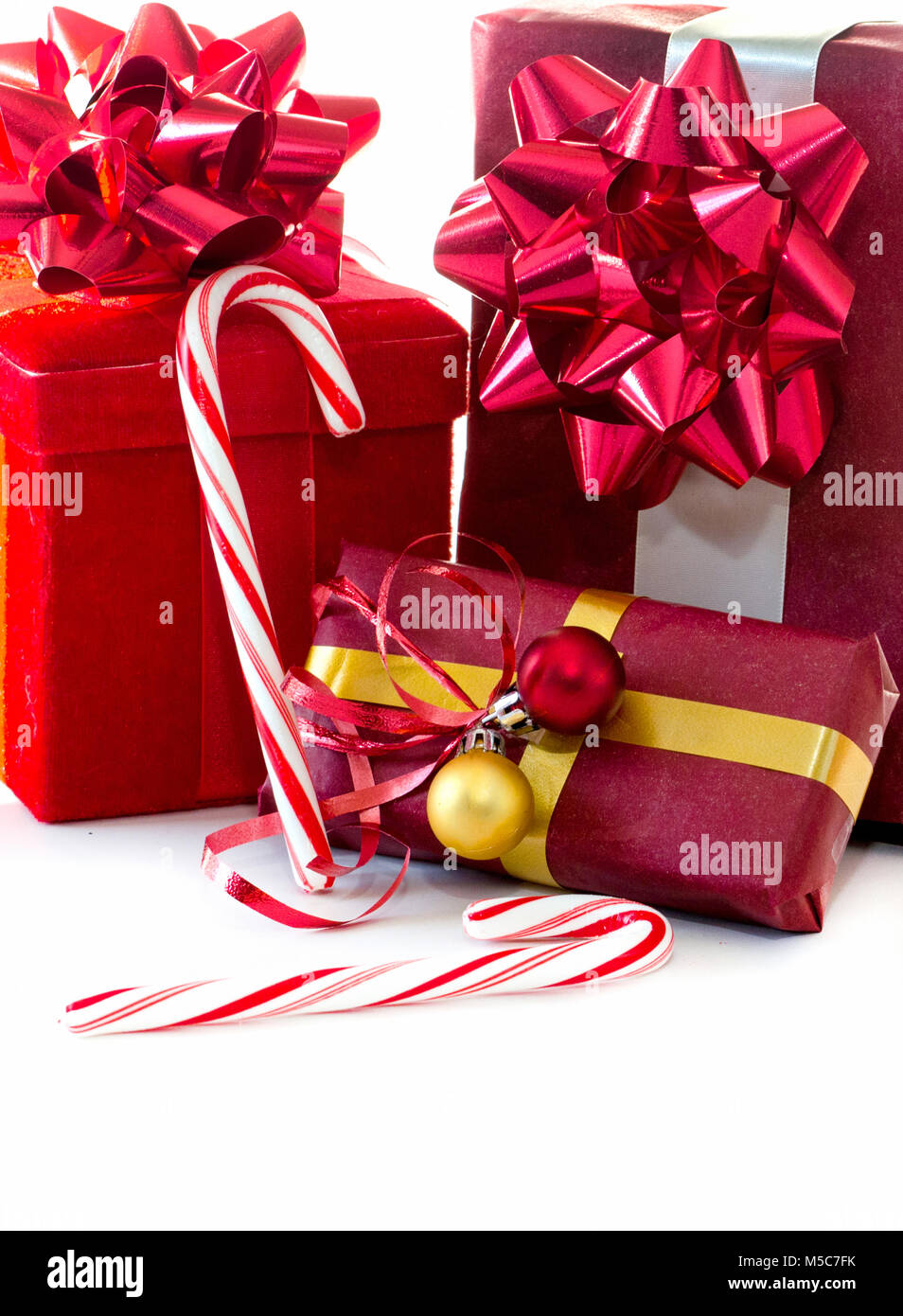 Boîtes enveloppées rouge avec des arcs et maison de garnitures sont affichés sur un fond blanc avec des cannes de bonbon Banque D'Images