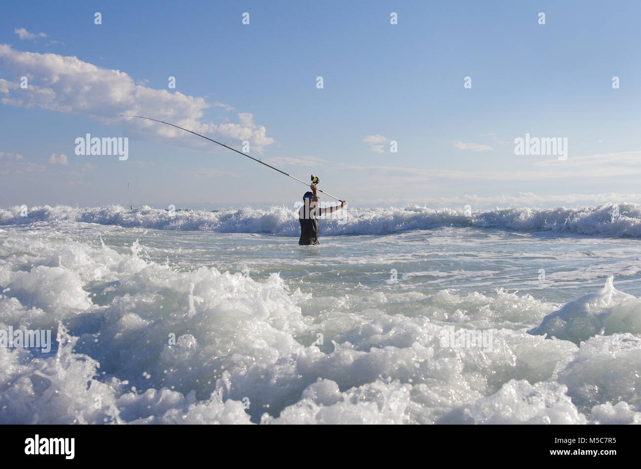 Pêcheur de surf dans les vagues. Scène de pêche. surf casting. Banque D'Images