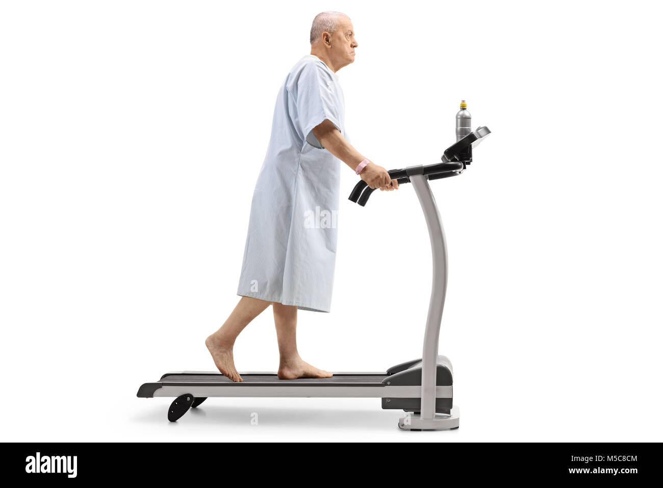 Profil tourné sur toute la longueur d'un patient âgé marcher sur un tapis roulant isolé sur fond blanc Banque D'Images