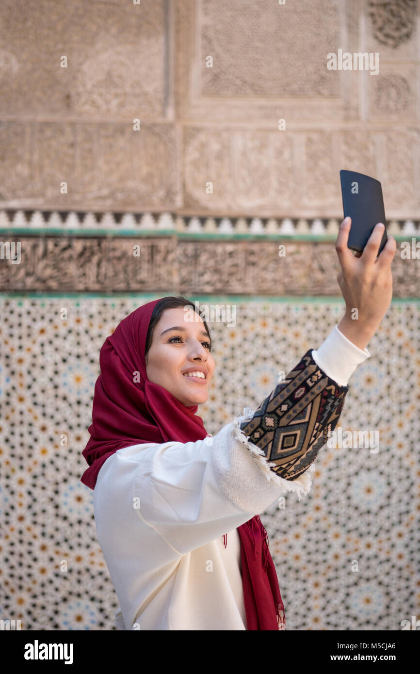 Femme musulmane en tenant avec selfies téléphone mobile en vêtements  traditionnels avec foulard rouge sur la tête Photo Stock - Alamy