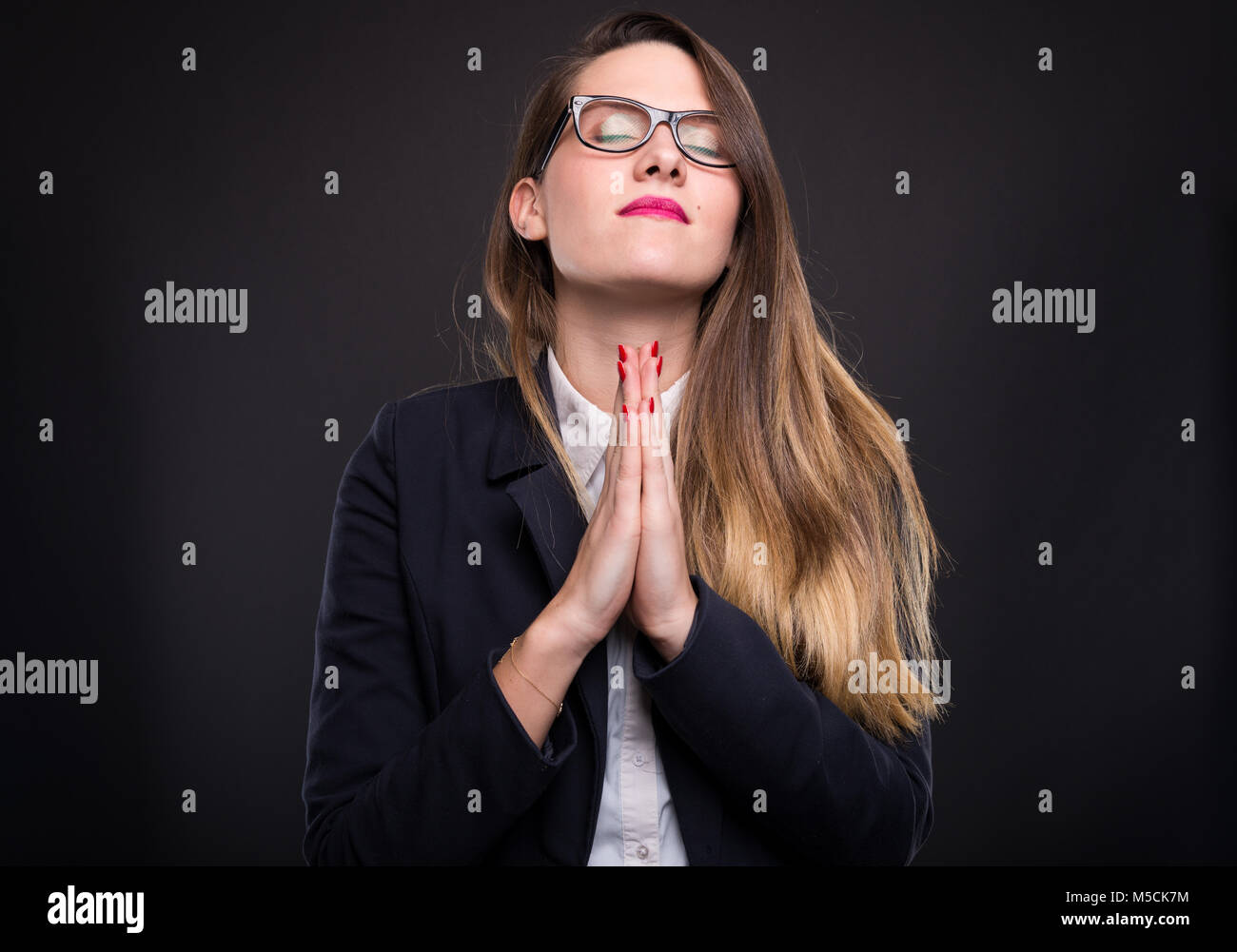 'Jeune femme met les mains dans la prière les espoirs de plan réussi réalisation sur fond sombre' Banque D'Images