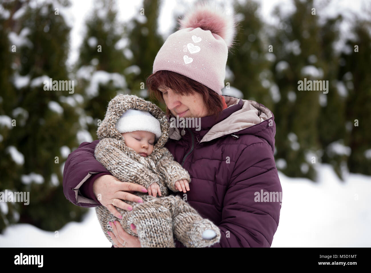 Grand-mère tenant peu bébé garçon en plein air, sur une journée d'hiver enneigée, ayant pris leur portrait Banque D'Images