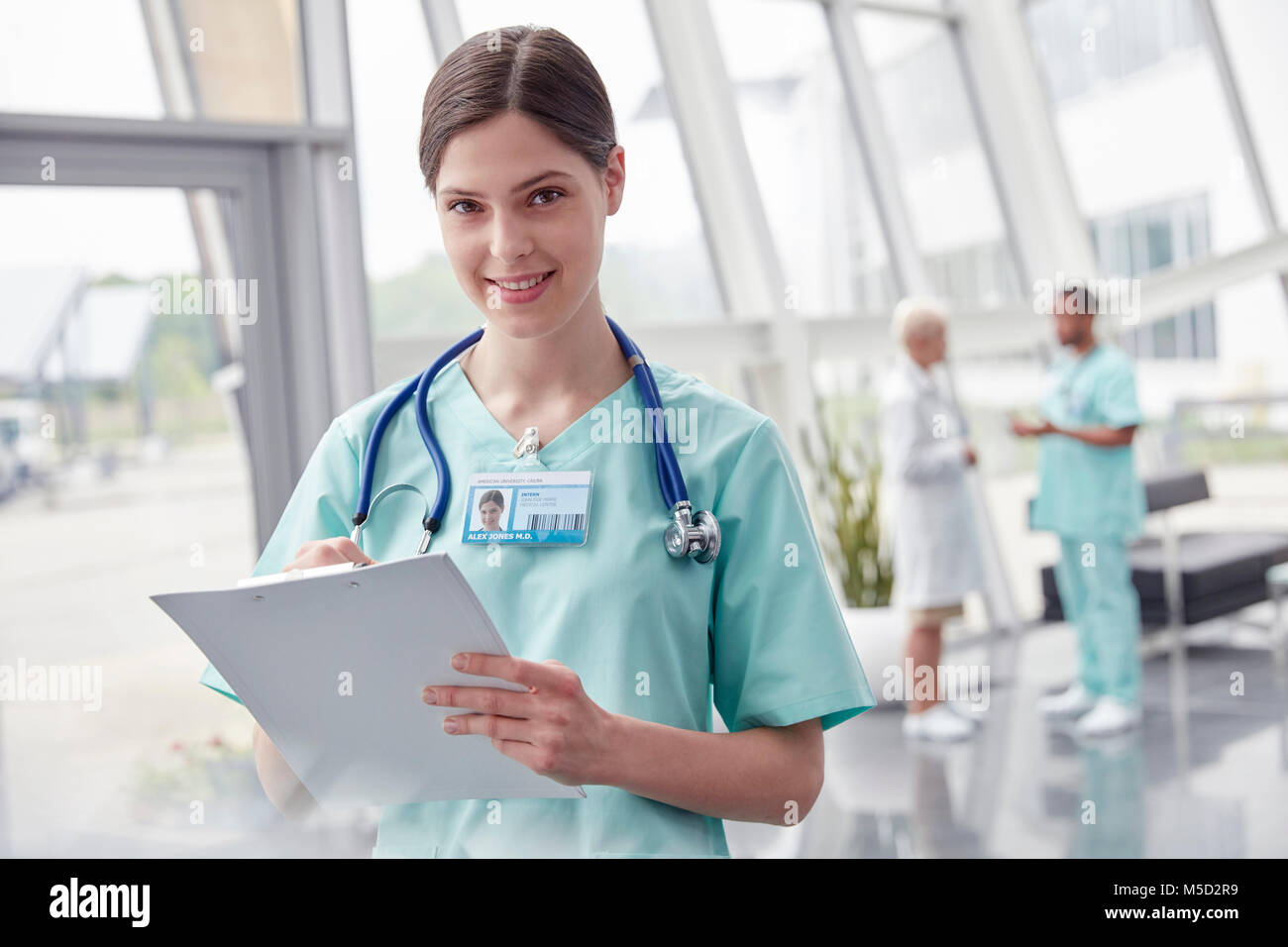 Portrait souriant, confiant infirmière avec presse-papiers à l'hôpital Banque D'Images