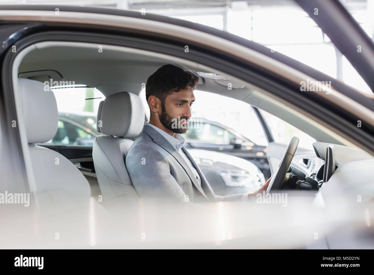 Client de sexe masculin assis dans le siège du conducteur de voiture neuve dans car dealership showroom Banque D'Images