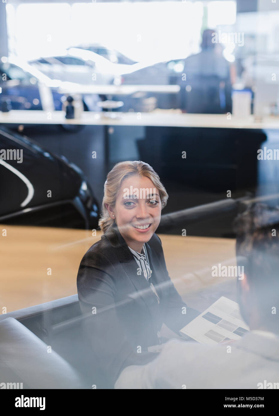Portrait smiling car saleswoman working in car dealership showroom Banque D'Images