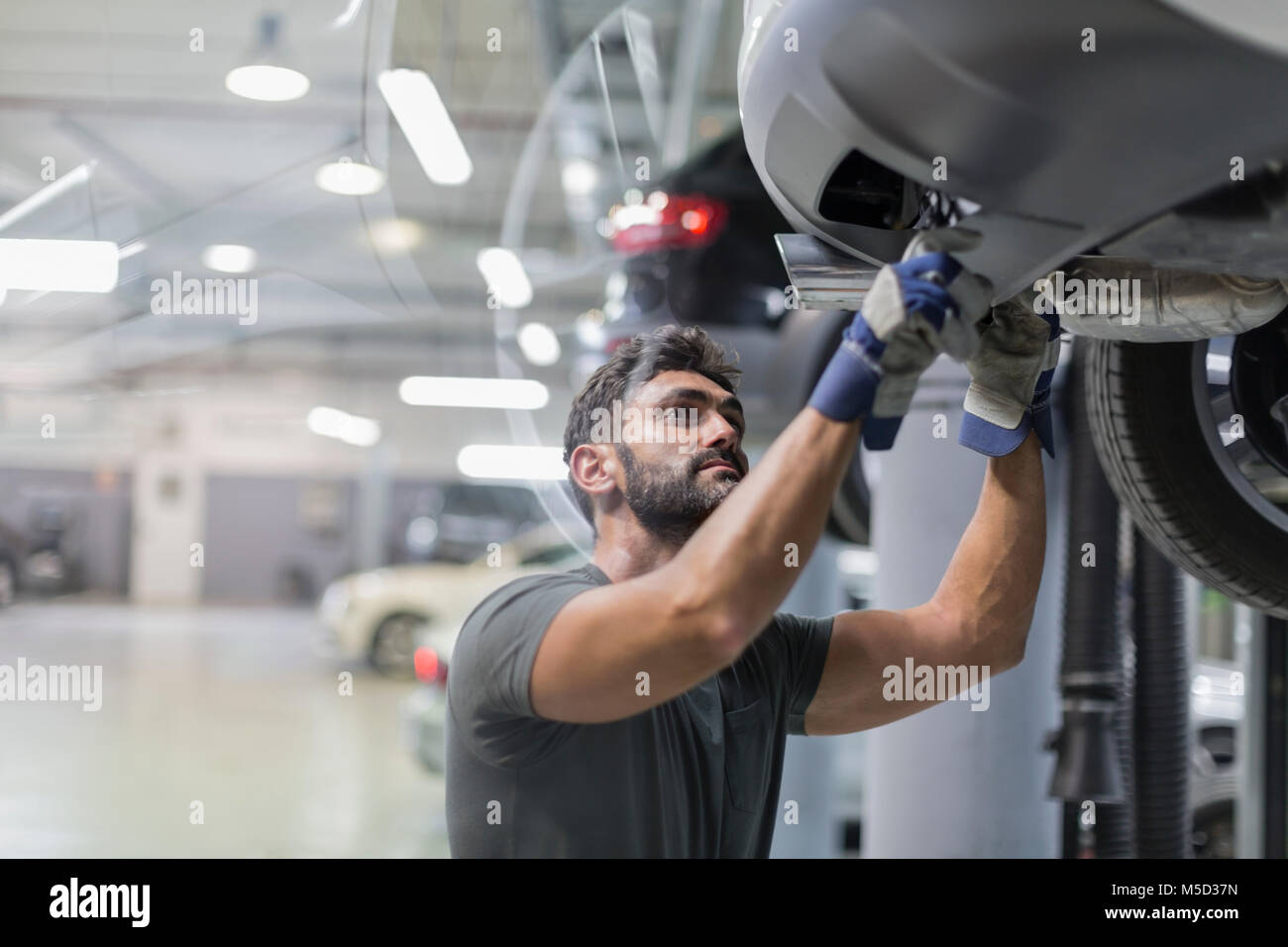 Mécanicien d'hommes travaillant sous location in auto repair shop Banque D'Images