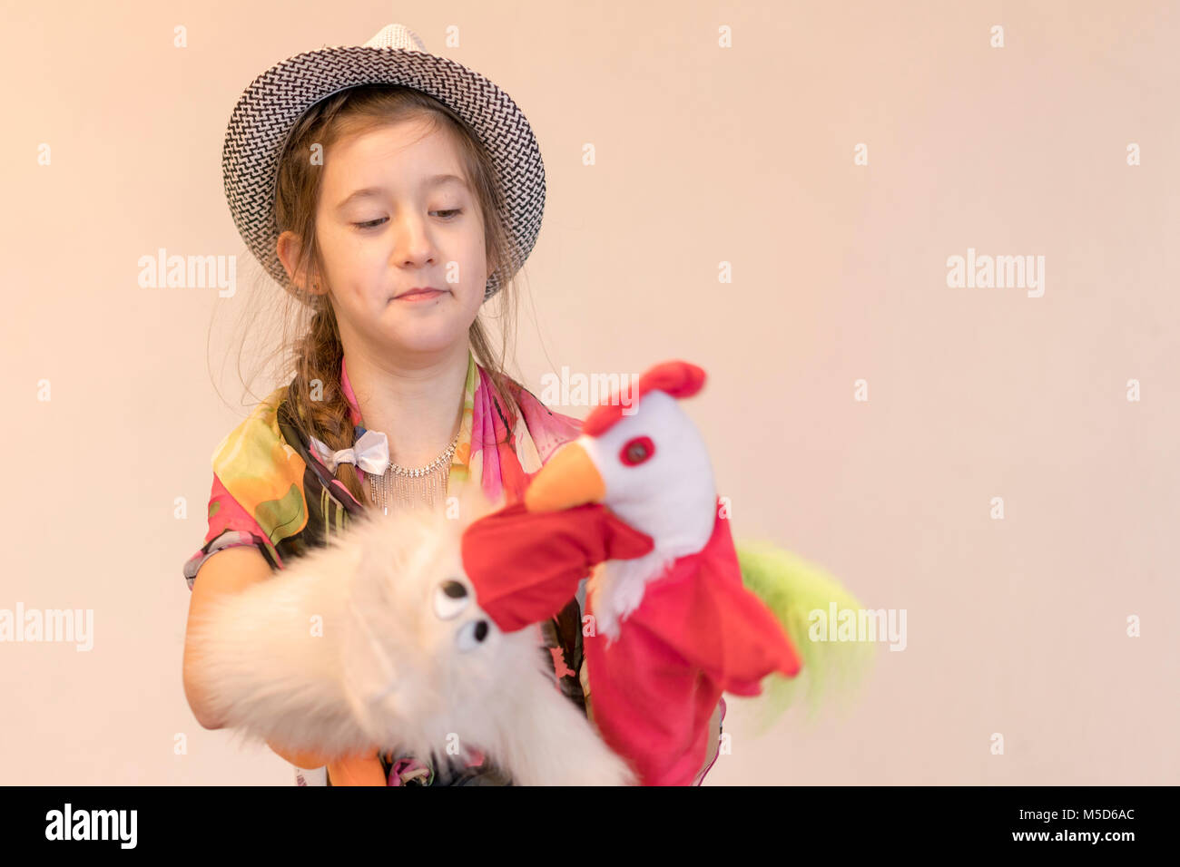 Fille 8 ans in Hat jouant dans le théâtre de marionnettes. Sur fond clair. copy space Banque D'Images