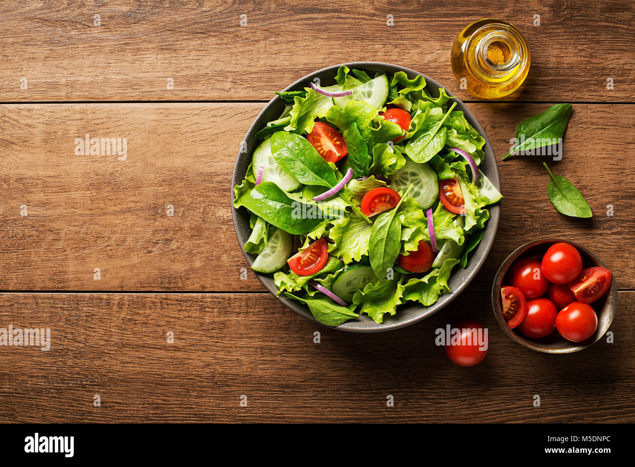 Salade verte avec tomate et légumes frais sur un fond de bois Banque D'Images