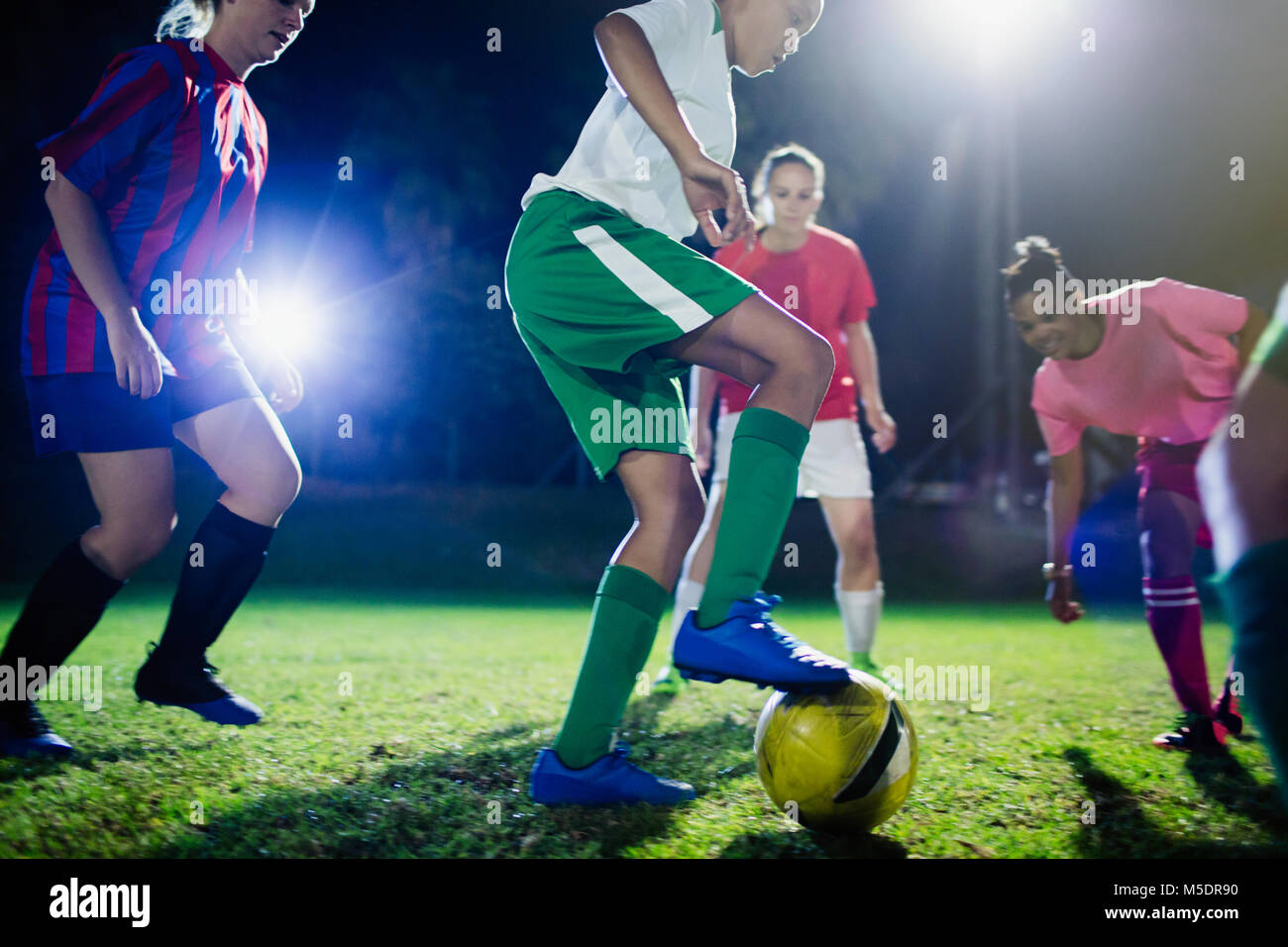 Les jeunes joueuses de soccer sur le terrain de jeu dans la nuit, les coups de la balle Banque D'Images