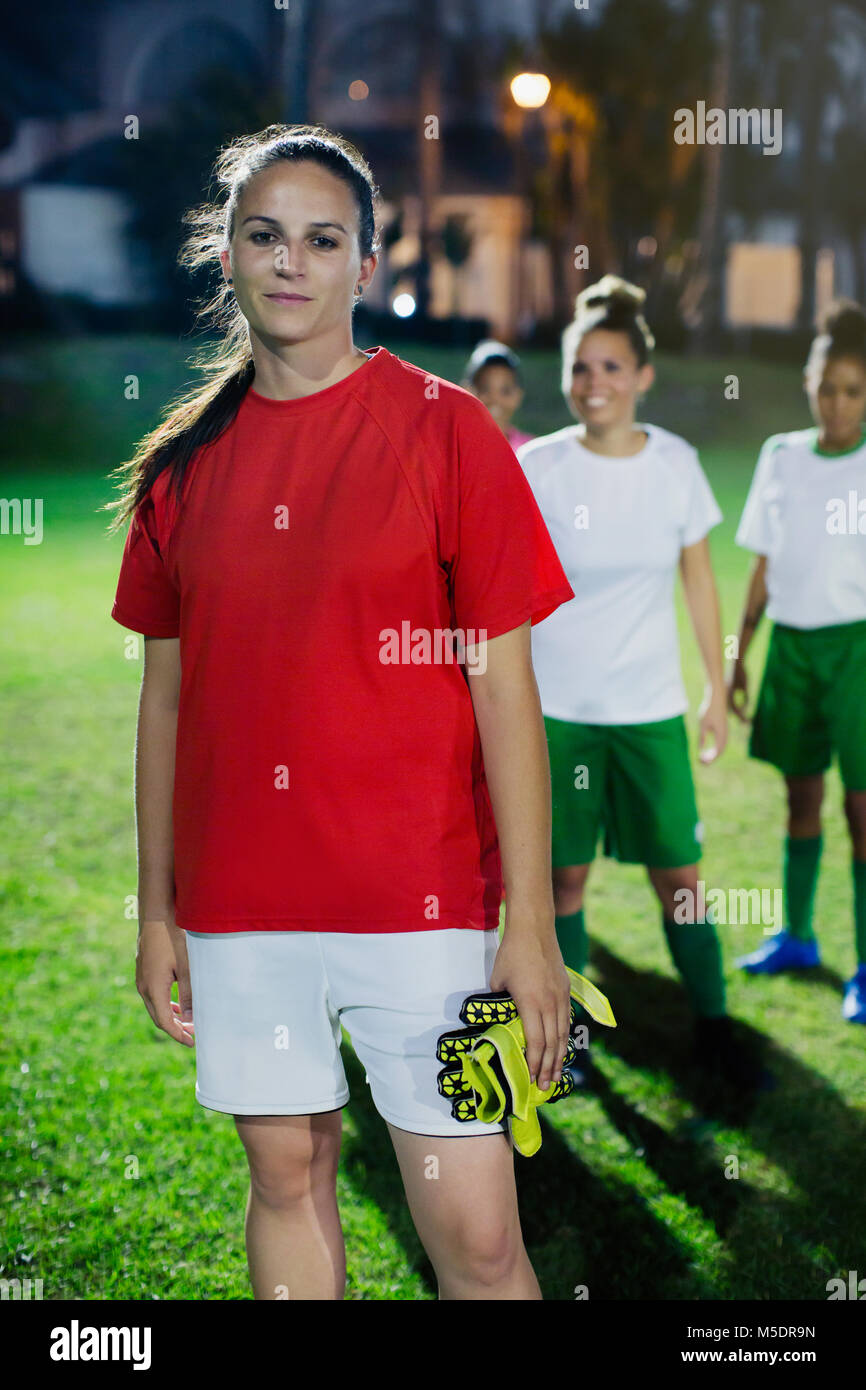 Portrait jeune femme confiant joueur de football sur terrain de nuit Banque D'Images