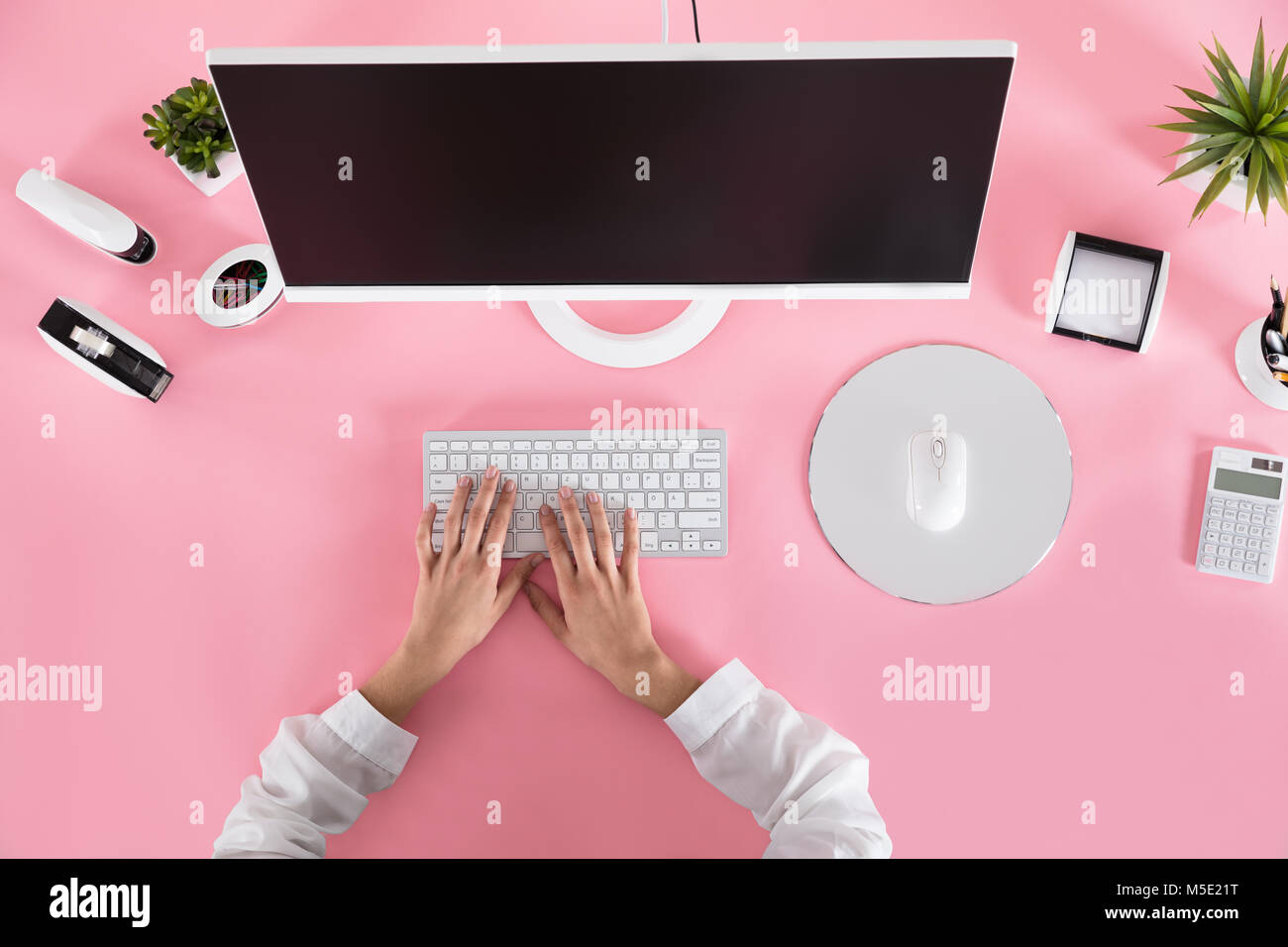 Les mains d'affaires sur le clavier sur le bureau rose sur le lieu de travail Banque D'Images