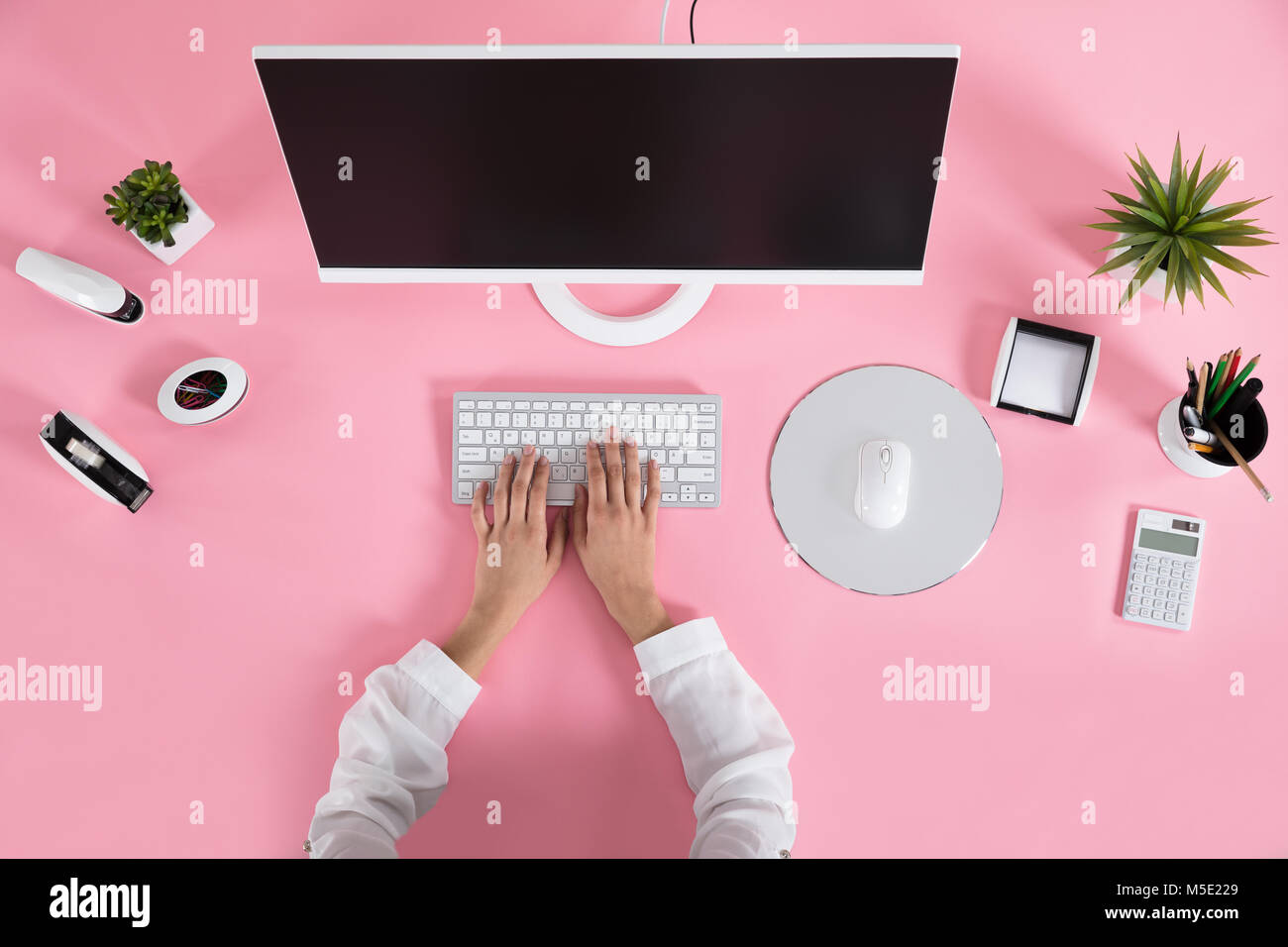 Les mains d'affaires sur le clavier sur le bureau rose sur le lieu de travail Banque D'Images