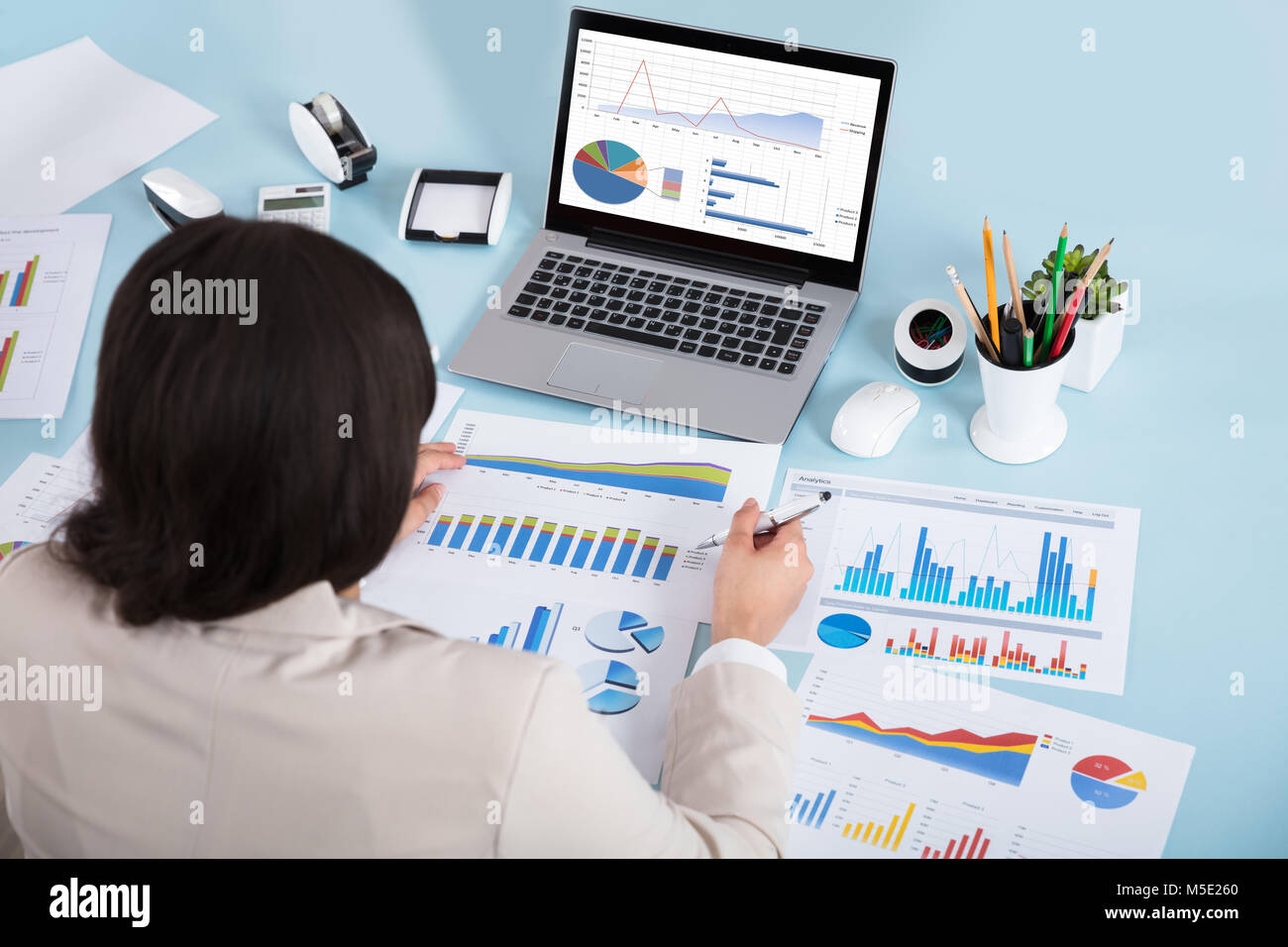 Close-up of a Businesswoman analyser divers graphiques sur bleu Desk In Office Banque D'Images