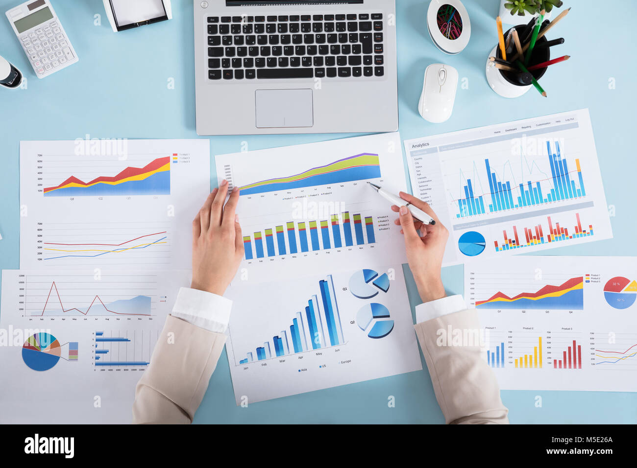 Close-up of a Businesswoman analyser divers graphiques sur bleu Desk In Office Banque D'Images