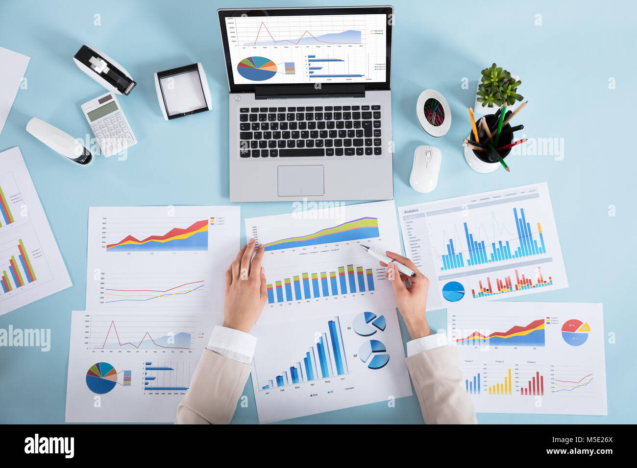 Close-up of a Businesswoman analyser divers graphiques sur bleu Desk In Office Banque D'Images