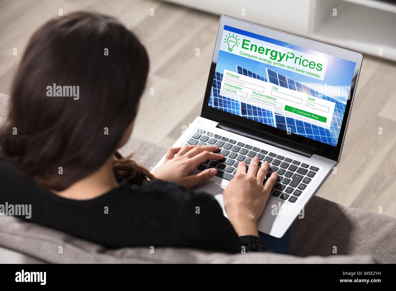 Femme assise sur la table à des prix de l'énergie sur les ordinateurs portables Banque D'Images
