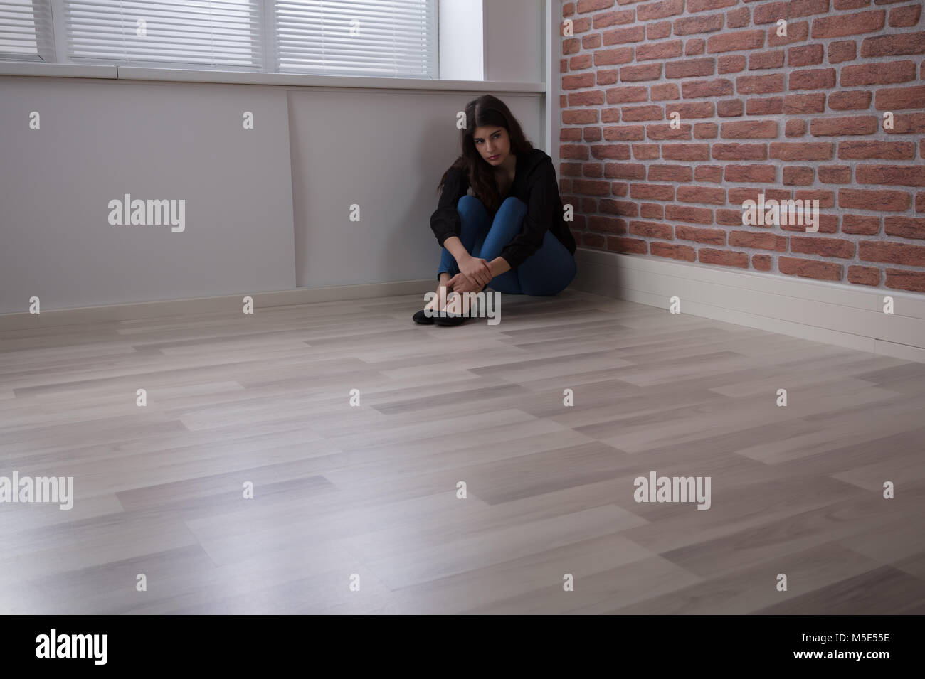 Triste Jeune femme assise sur le coin de la pièce à la maison Banque D'Images