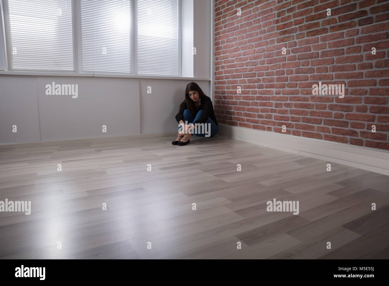 Triste Jeune femme assise sur le coin de la pièce à la maison Banque D'Images