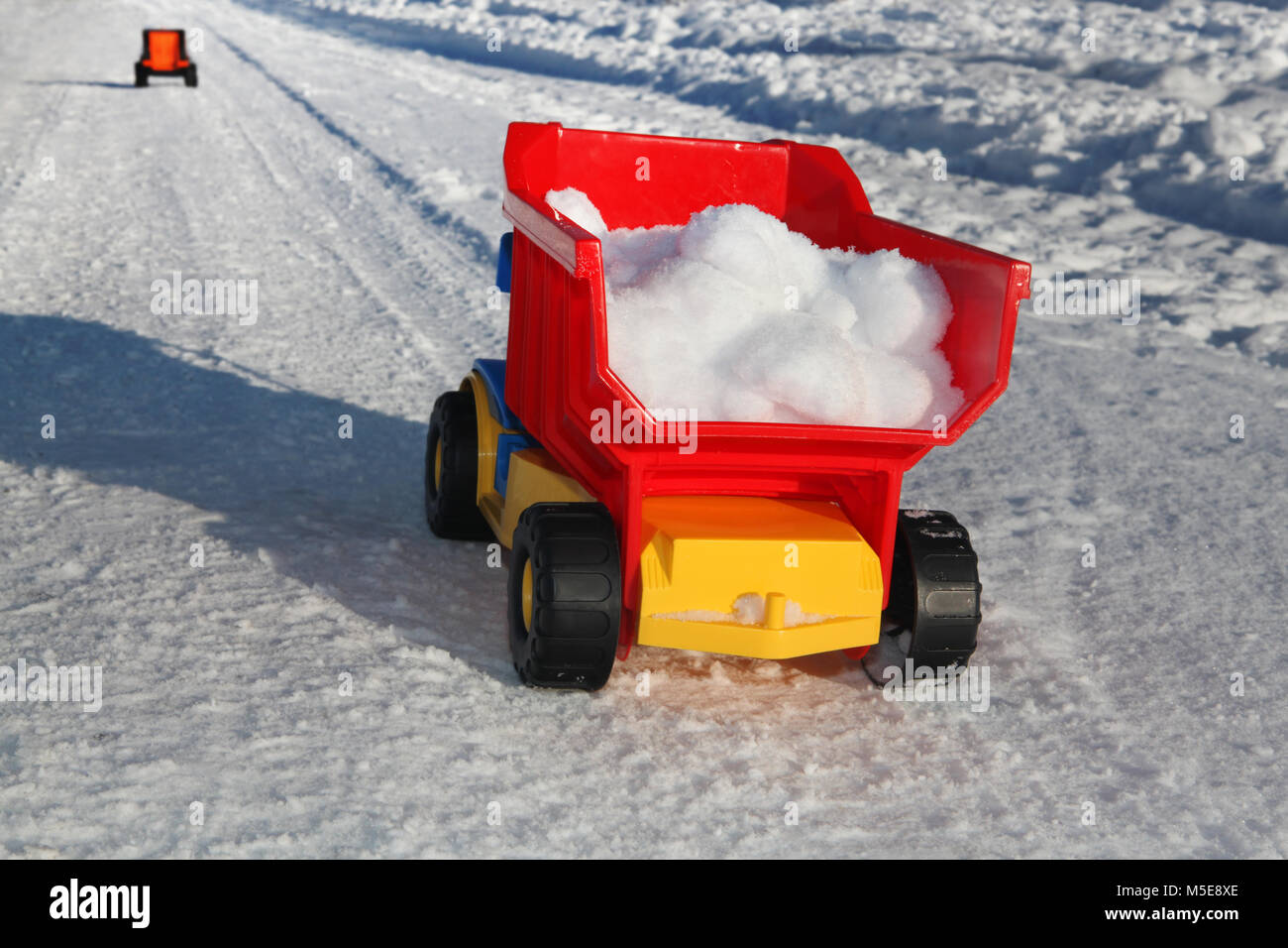 Camion jouet enlève la neige sur la route en hiver Banque D'Images