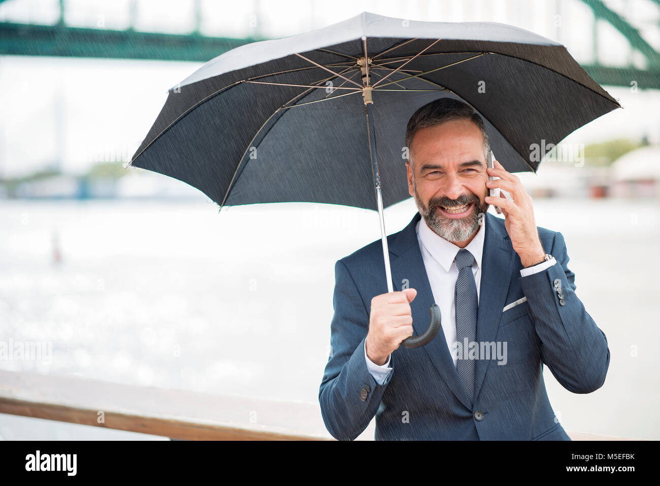 L'homme d'affaires un jour de pluie, de discuter avec un collègue et holding an umbrella Banque D'Images