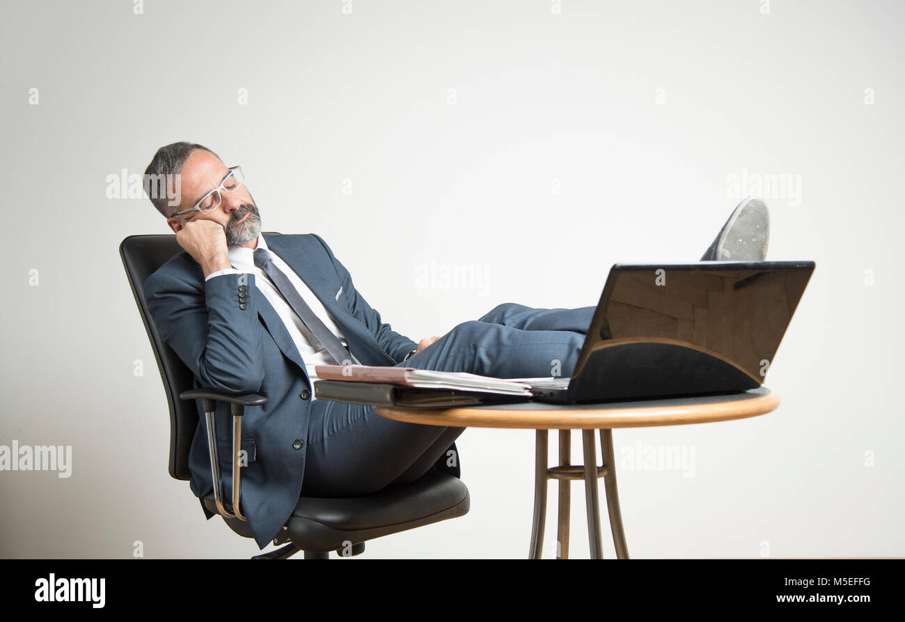 Ennuyer business man est en train de dormir dans son bureau, allongé sur sa  chaise avec ses jambes sur son bureau 24 Photo Stock - Alamy