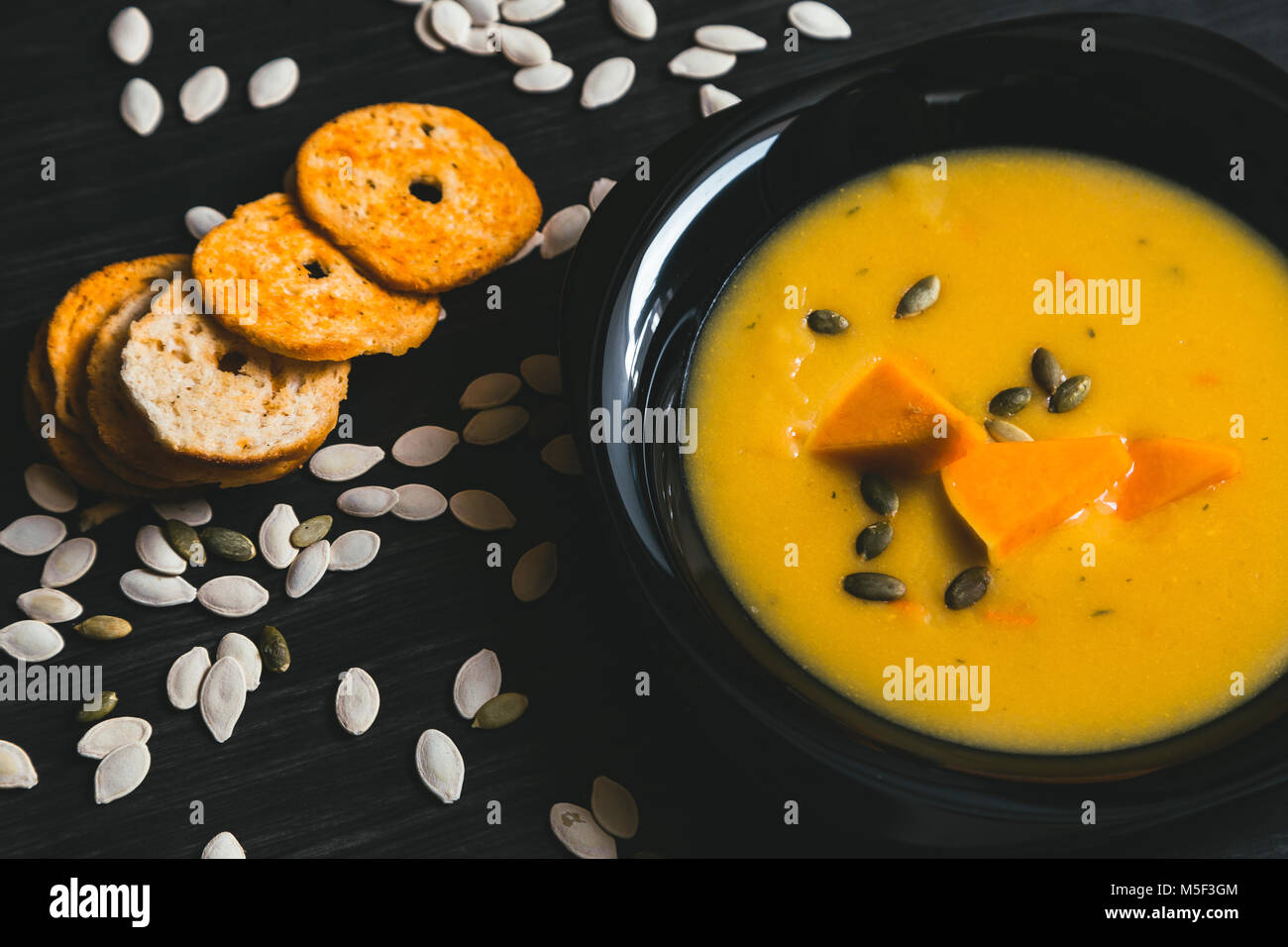 Soupe au potiron avec des tranches de citrouille fraîche sur un côté. Fond en bois foncé Banque D'Images