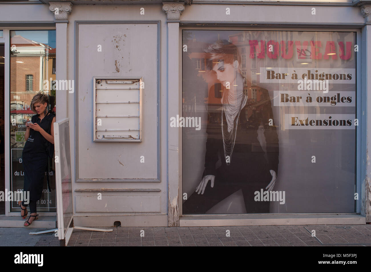 Perpignan, France. Fille sur la porte d'un salon de coiffure. Banque D'Images