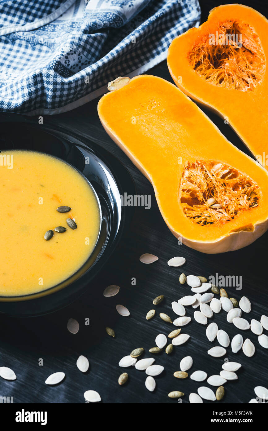 Soupe au potiron avec des tranches de citrouille fraîche sur un côté. Fond en bois foncé Banque D'Images