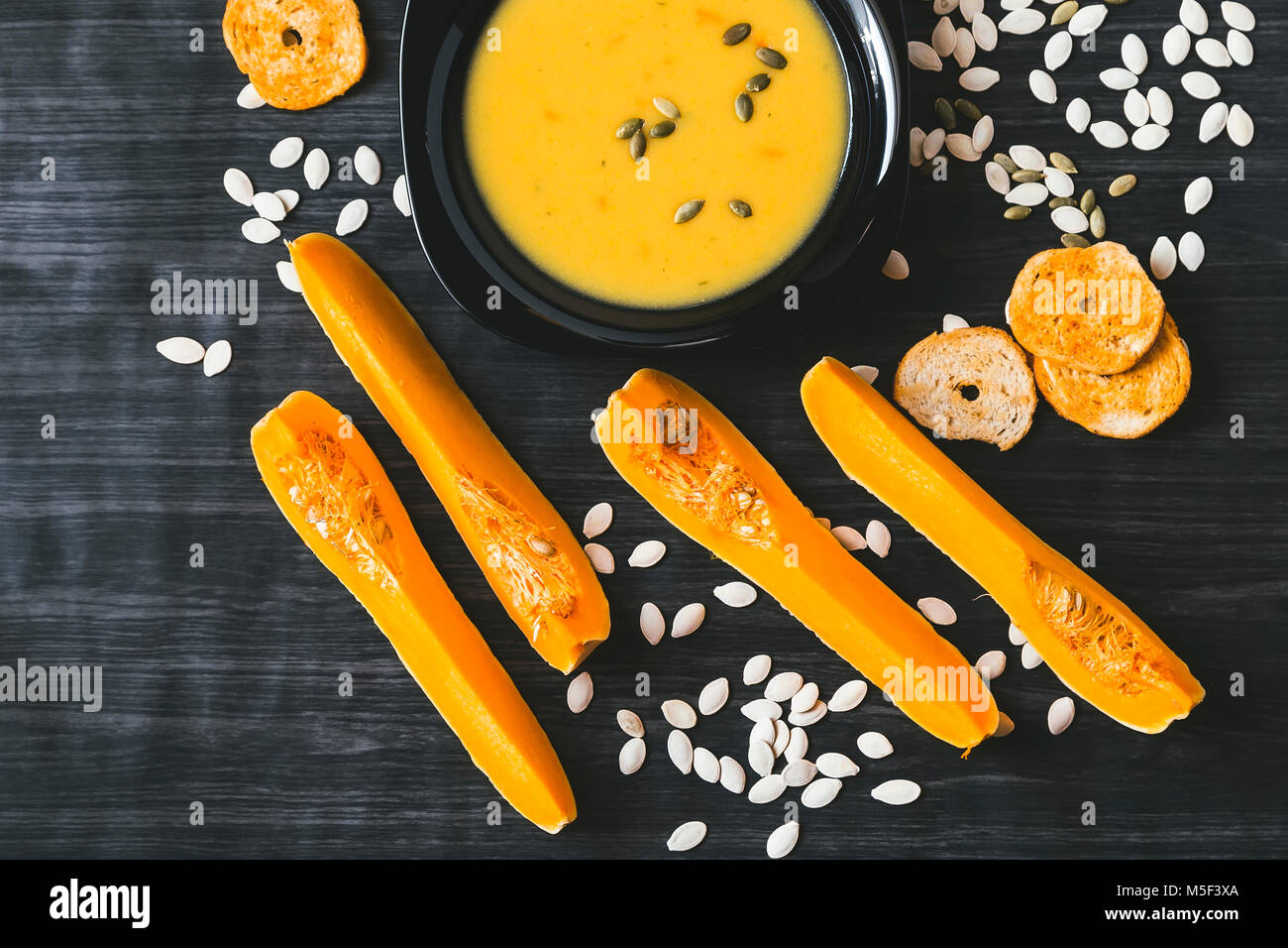 Soupe au potiron avec des tranches de citrouille fraîche sur un côté. Fond en bois foncé Banque D'Images