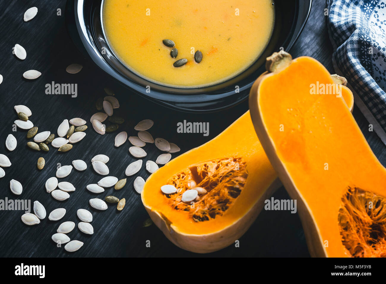 Soupe au potiron avec des tranches de citrouille fraîche sur un côté. Fond en bois foncé Banque D'Images