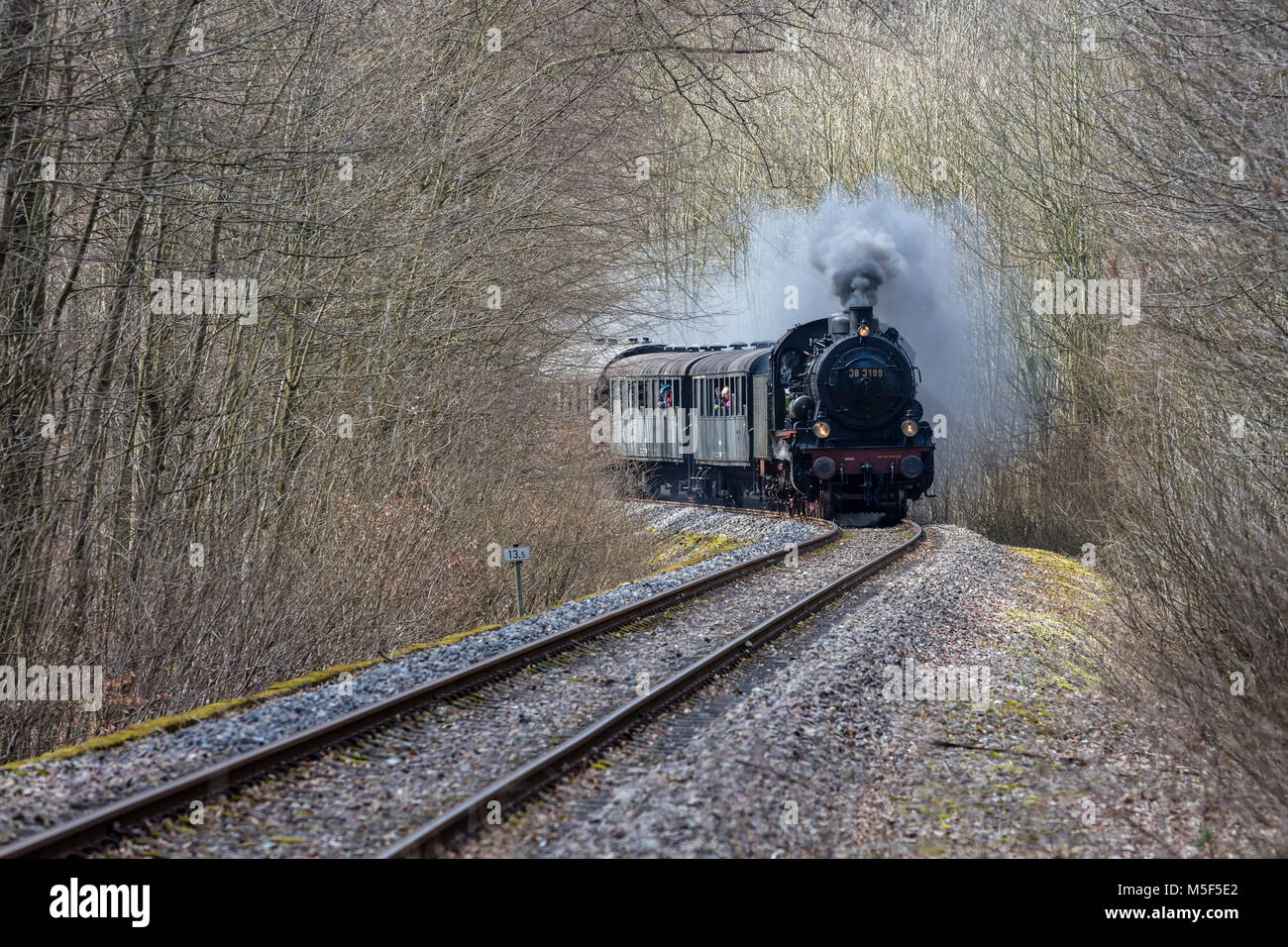 Train à vapeur historique roulant à pleine vitesse à travers une forêt d'hiver Banque D'Images