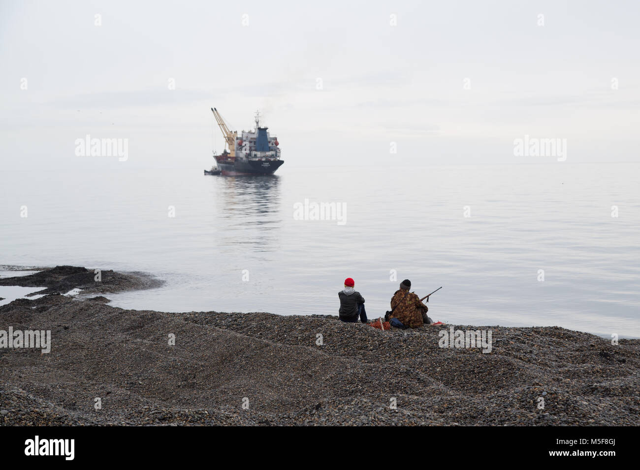 Uelen, Chukotski région, Russie - Règlement Uelen, 26 juin 2017 : Les chasseurs regarder le navire. Banque D'Images