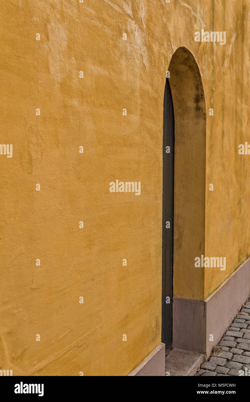 Mur en stuc jaune avec porte marron Banque D'Images