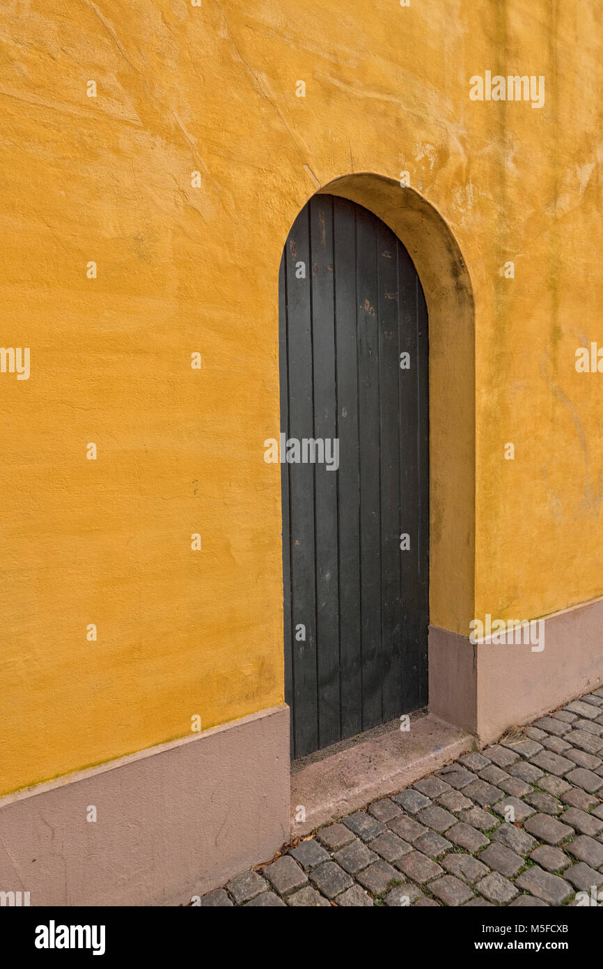 Mur en stuc jaune avec porte marron Banque D'Images