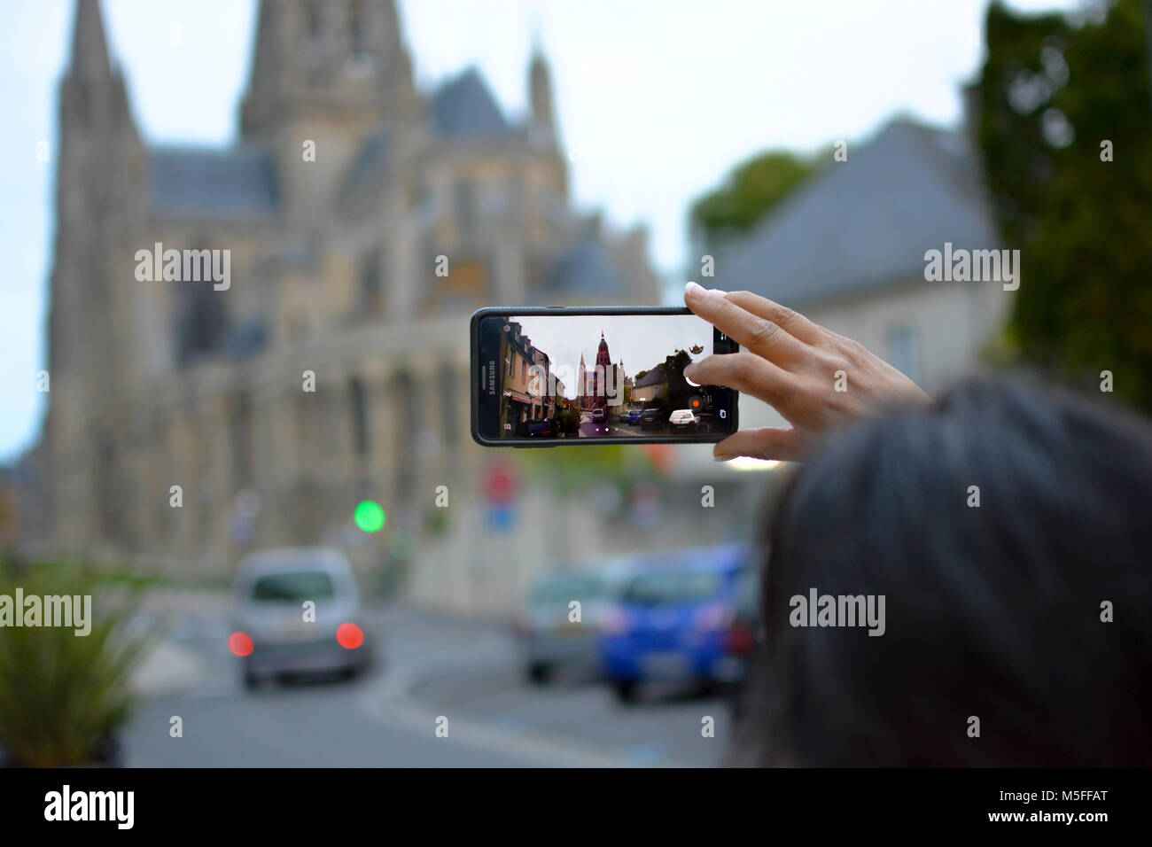 Un touriste capture une photo avec son téléphone portable du quartier gothique de la cathédrale de Bayeux à Bayeux France, Normandie. Banque D'Images