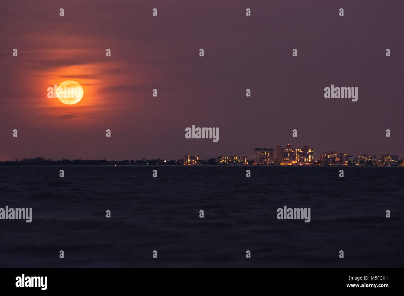 Une pleine lune rouge s'élève au-dessus des grands condos cette ligne de l'horizon's edge sur Fort Myers Beach en Floride. Banque D'Images