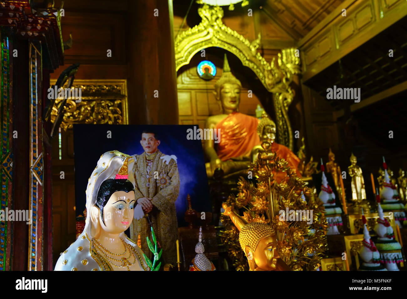 Femme statue bouddhiste en lumière tamisée à l'intérieur de Temple Bouddhiste grand Bouddha en or entouré de cadeaux pour les moines et photo du roi et grand Bouddha Banque D'Images