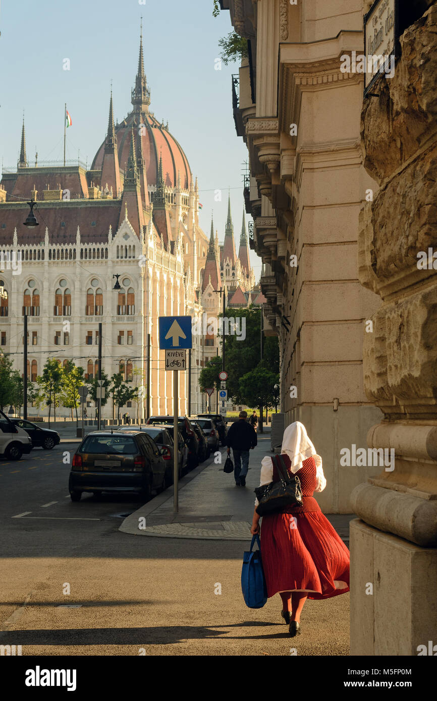 Femme portant une robe traditionnelle hongroise marche sur Budapest street contre l'édifice du Parlement Banque D'Images