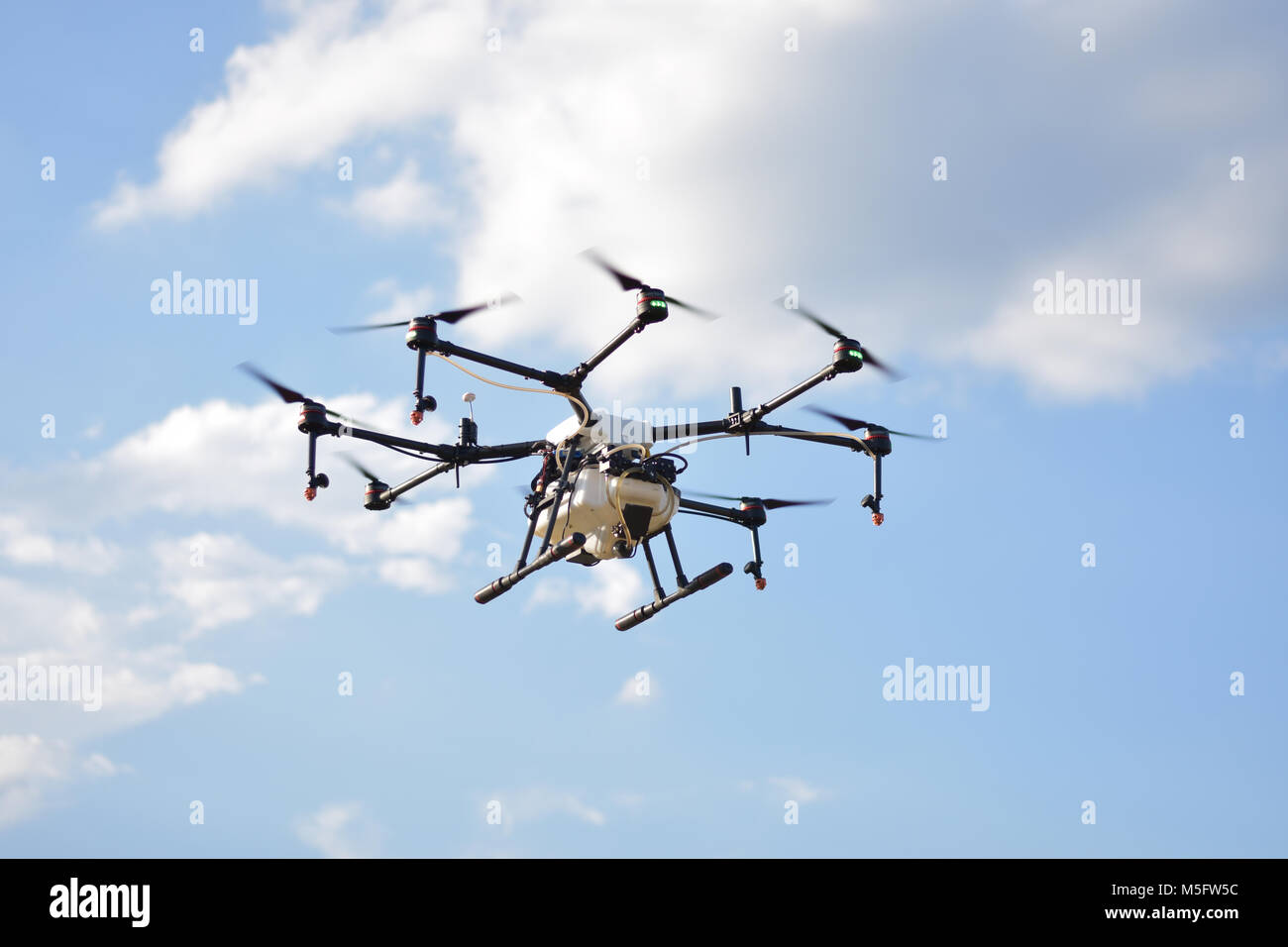 L'agriculture, de vol de drone drone photo image de l'agriculture portent un réservoir d'engrais liquide volant dans le ciel bleu se préparent à le vaporiser dans l'agriculture sont Banque D'Images