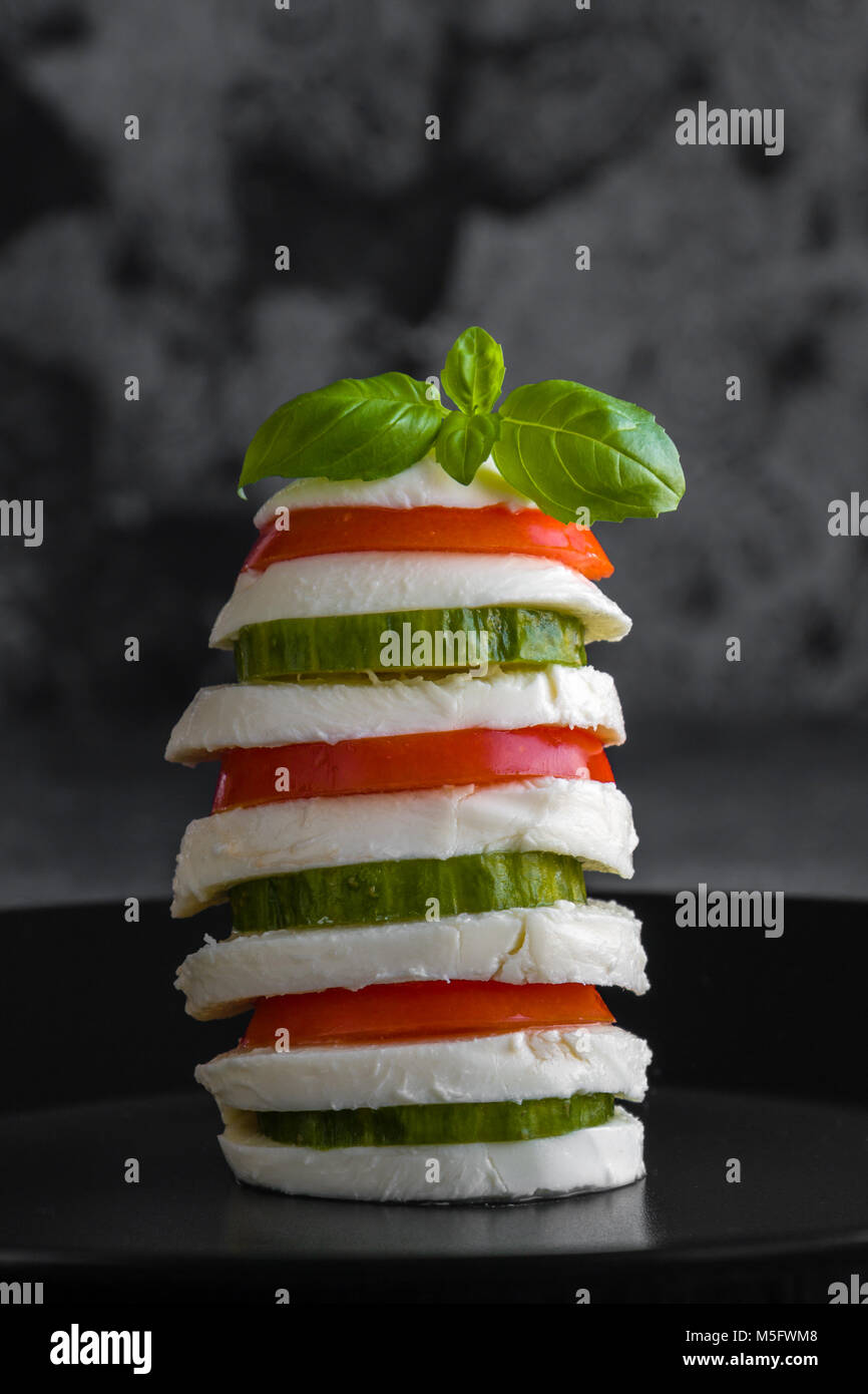 La mozzarella empilés avec des légumes sur fond sombre Banque D'Images