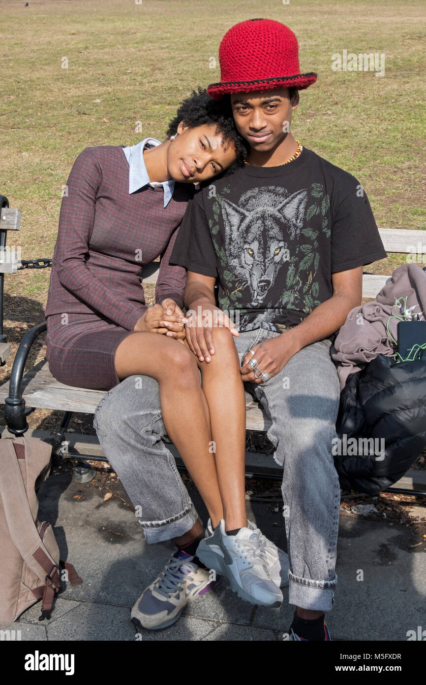 Un joli jeune couple assis au soleil avec leurs jambes entrelacées sur une chaude journée d'hiver. Dans la région de Washington Square Park, à New York. Banque D'Images