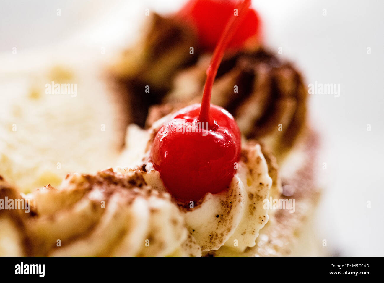 Glace rouge cerise sur haut de gâteau, gros plan, macro, selective focus. Détail de la décoration de gâteau, blanc crème, garnir de cerises douces, traiter. Banque D'Images