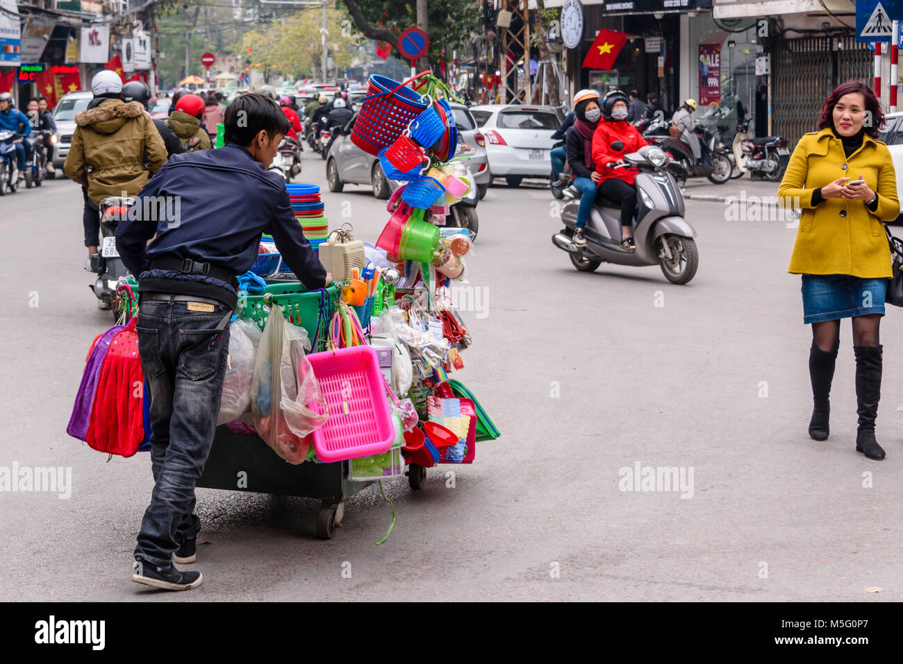 Un homme pousse sa charrette vietnamiens jouets contenant le long d'une rue à Hanoi, Vietnam. Banque D'Images